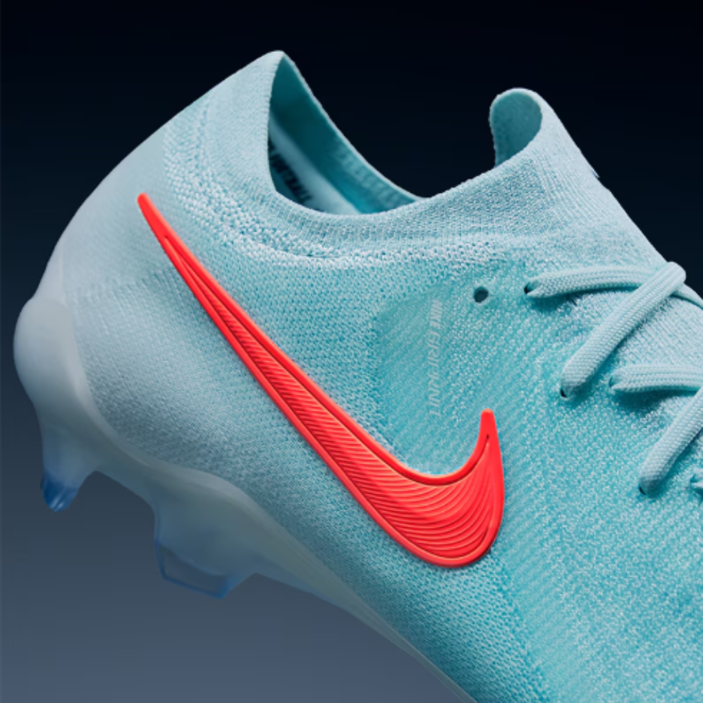 Chuteira de futebol Nike Phantom GX II Elite FG Mad Energy em close-up, destacando a cor verde aurora, vermelho e preto. A imagem mostra a textura Gripknit da parte superior, o sistema de travas Cyclone 360 e o logo da Nike.